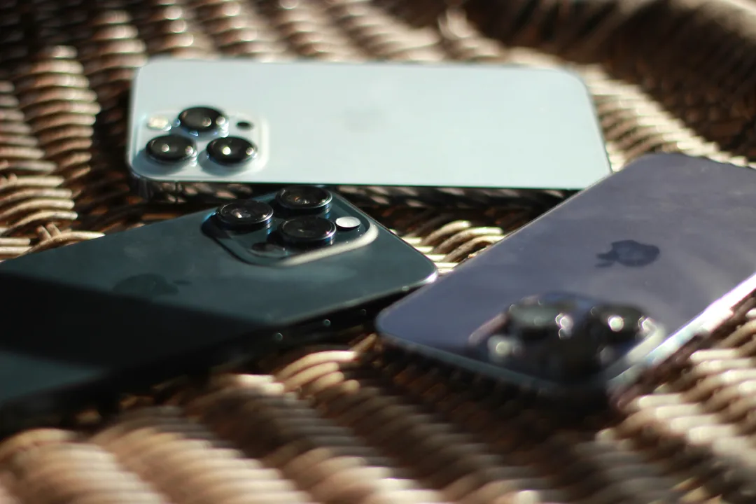 Three phones lying face down on a chair in the sun